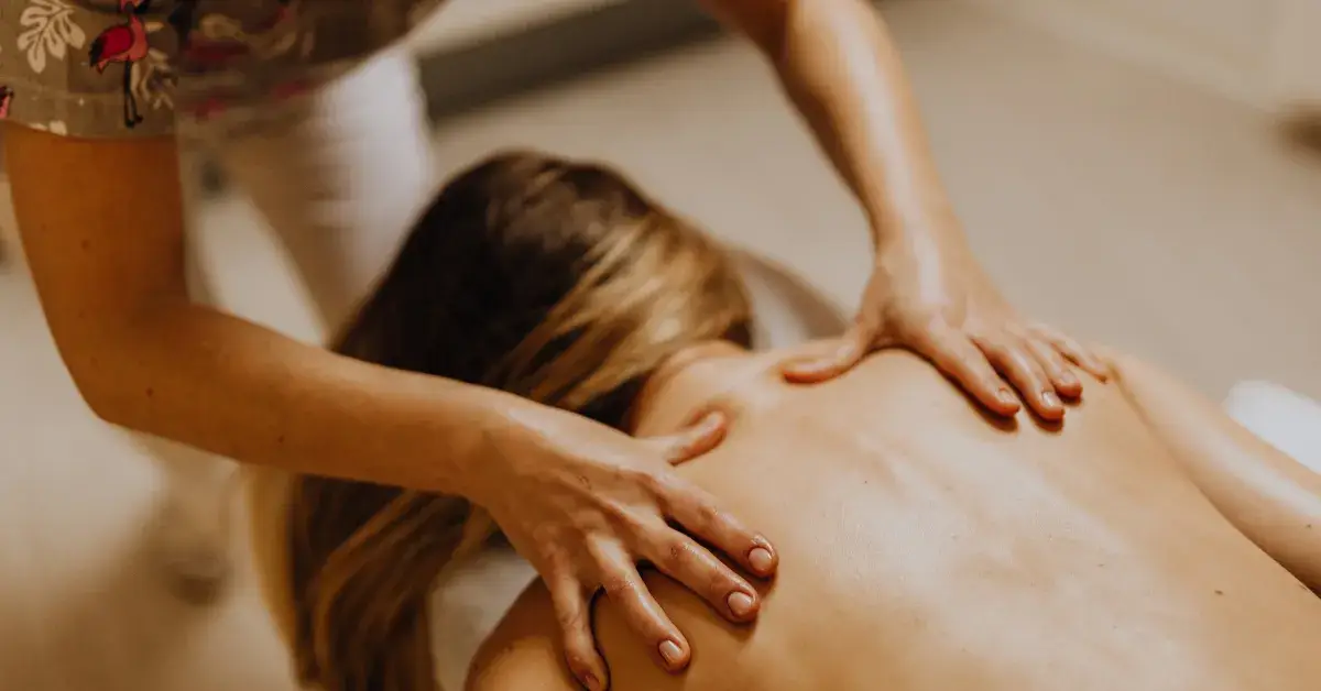  Close-up of a therapist performing a back massage on a woman lying on a table.